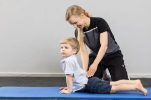dziecko na macie podczas rehabilitacji wykonuje ćwiczenia z fizjoterapeutką